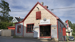 A classic old blacksmith shop in Lunenburg Nova Scotia. A simple one story wooden shingled building with red trim and big double door entrance.